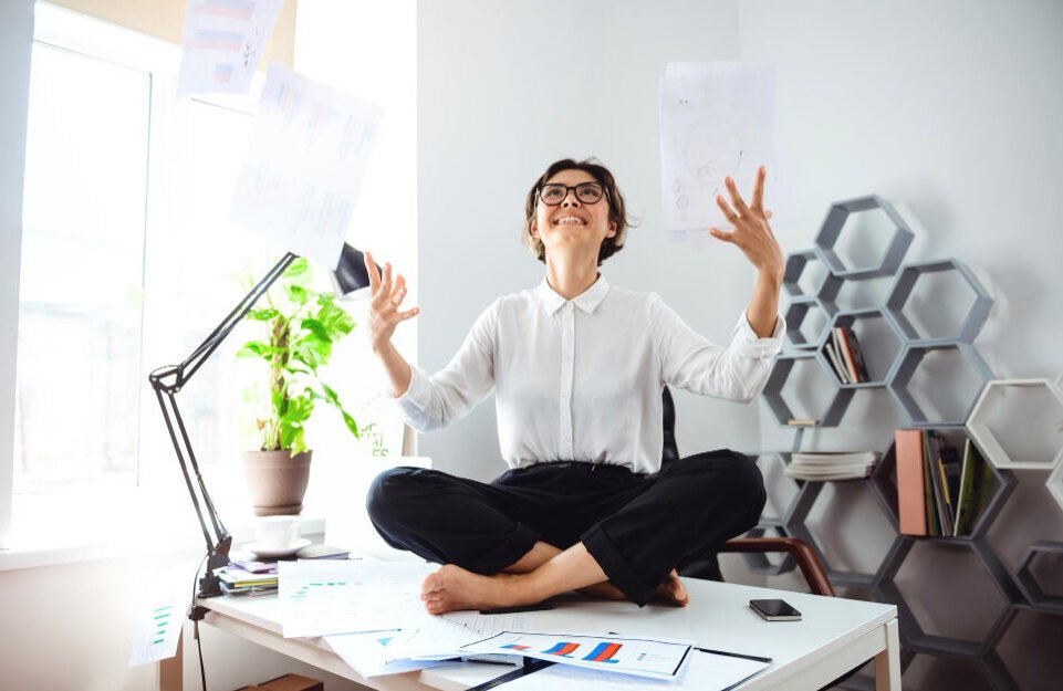 young-beautiful-businesswoman-glasses-smiling-throwing-up-papers-sitting-table-workplace-office